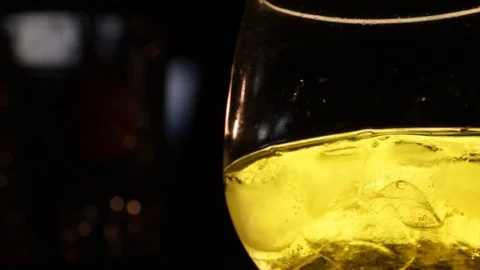 Bartender put an ice cube in a glass - yellow drink on black background Stock Footage 75164953