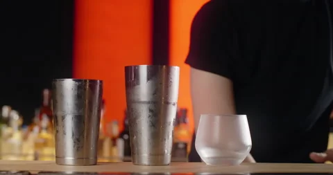 Bartender puts big ice cube to the frozed cocktail glass by forceps, making the Stock Footage 156392533