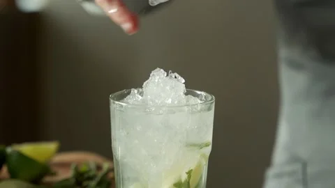 Bartender puts broken ice in a glass while making a mojito cocktail Stock Footage 153460270