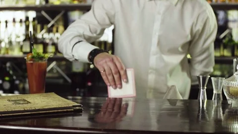 The bartender puts a glass on the coaster next to the menu in the bar slow Stock Footage 76719415