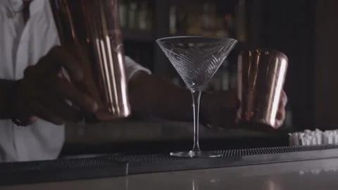 A bartender puts his shaker on the bar next to an empty cocktail glass Stock Footage 135451990