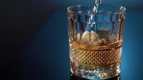 Bartender puts a piece of ice in a glass and pours the whiskey. Stock Footage 136504141