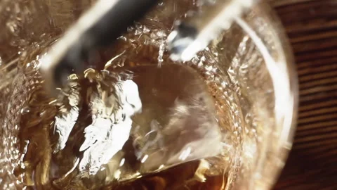 Bartender puts a piece of ice in a glass with liquor, slow motion. Stock Footage 136547580