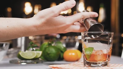 Bartender puts a piece of lime and pours liquor from jigger into glass. Vídeos de archivo 106892892