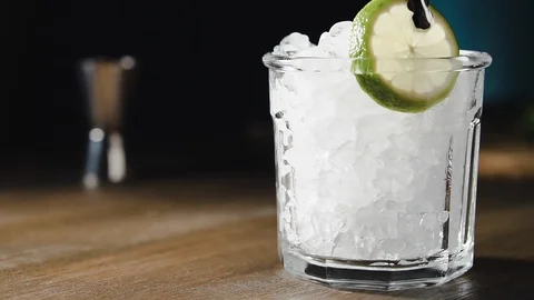 Bartender puts slice of lime into glass with ice, slow motion. Lime cocktail, Stock Footage 124012785