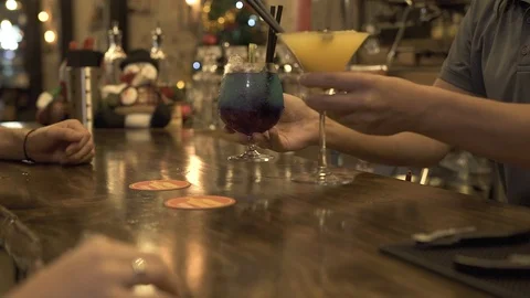 Bartender putting alcoholic cocktail at bar table for client in evening cafe Stock Footage 101930680