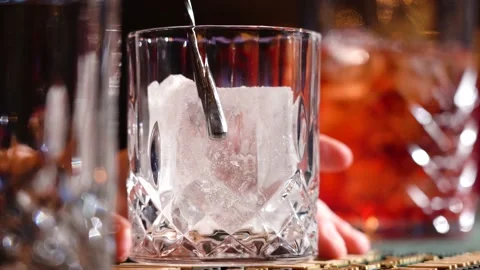 Bartender putting crystal ice cubes  glass while preparing  alcoholic cocktail Vidéo 149063010