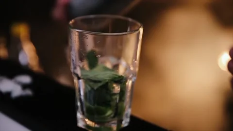 A bartender is putting professional crystal ice cubes in a glass while preparing Stock Footage 148963870