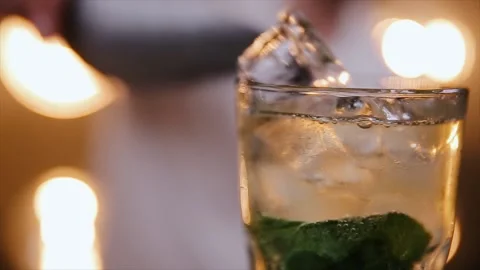 Bartender putts crystal ice cubes in a glass while preparing cocktail mojito Stock Footage 136197571