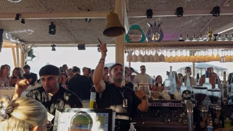 Bartender Rings Bell as Crowd Celebrates at Beach Bar Stock Footage 342221874