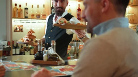 Bartender serving dinner to a happy couple chatting Stock Footage 171167349