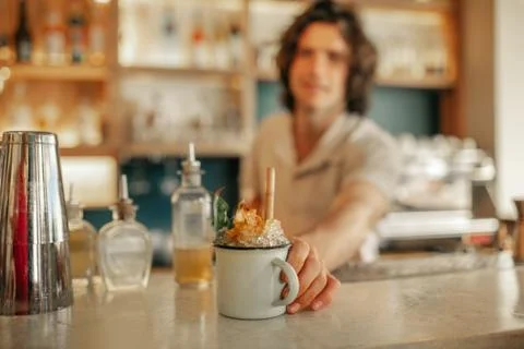Bartender serving drinks behind the counter of a trendy bar Stock Photos