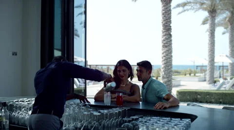 Bartender serving drinks to Expat couple at counter. Stock Footage 64110803