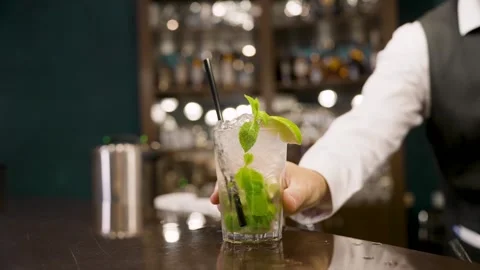Bartender serving mojito cocktail with mint and lime in dimly lit bar 스톡 동영상 341898234