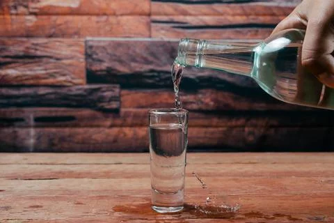 Bartender serving tequila from bottle to shot glass making splash 写真素材