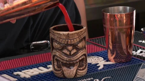 Bartender serving a Tiki red cocktail drink into a face-shaped glass 4K Stock Footage 196821402