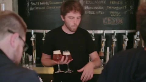 Bartender Serving Two Craft Beers To Clients Handheld Shot 库存影片 344303929