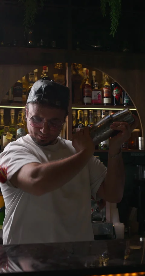 Bartender shaking a cocktail in a cocktail shaker, preparing mixed alcoholic Stock Footage 312355749