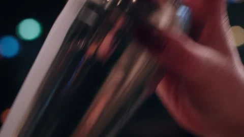Bartender Shaking Cocktail Shaker with Both Hands at Lively Night Bar Stock Footage 328974109