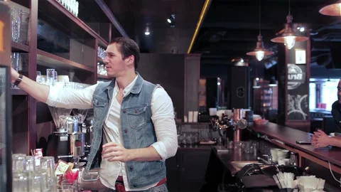 Bartender skillfully checks glass purity while a cheerful group celebrates Stock Footage 311812266