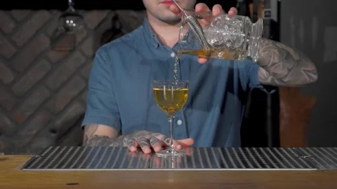Bartender skillfully pouring a vibrant cocktail for an eager customer Stock Footage 311649787