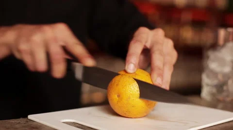 Bartender slicing orange to use in mixed drink Stock Footage 63297691