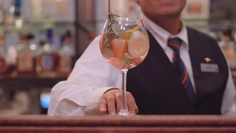 Bartender sliding Gin Tonic towards the camera in a hotel bar Stock Footage