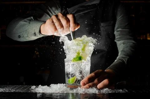 Bartender squeezing juice from fresh lime using a citrus press and splashing  Stock-Fotos