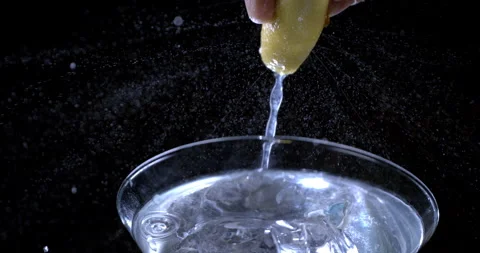 Bartender squeezing lemon while preparing alcoholic cocktail with ice cubes Video stock 269381309
