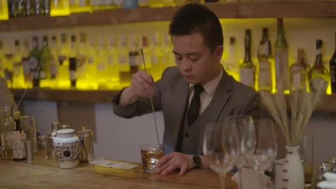 Bartender Stirring Drink at Bar Counter in Beijing with Bottles Displayed Behind Stock Footage 345753579