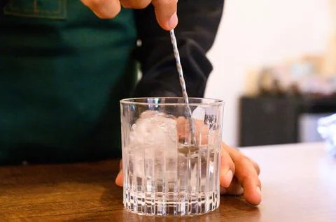 Bartender stirring ice in an old fashioned glass Stock Photos