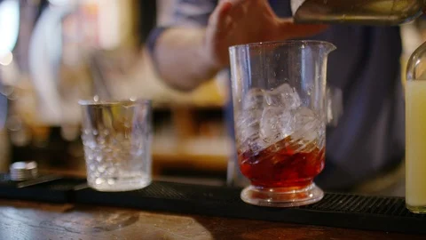Bartender stirring a Negroni cocktail before serving Stock Footage 102448651