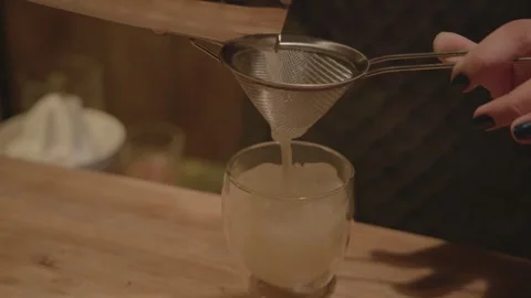Bartender Straining and Pouring Cocktail Over Ice in Glass at Bar in Beijing Stock Footage 345748198