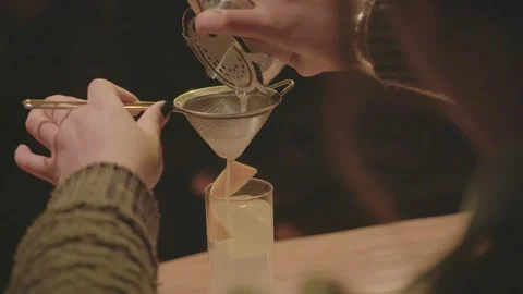 Bartender Strains Fresh Cocktail Into Citrus-Garnished Glass at Bar in Beijing Stock Footage 345747034