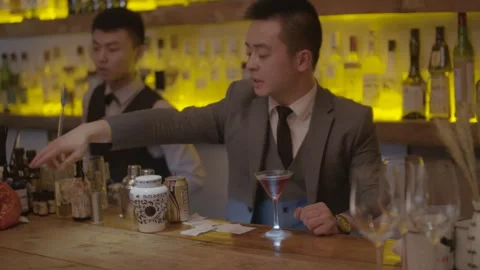 Bartender in Suit Preparing Cocktail at Bar Counter in Beijing Nightlife Scene Stock Footage 345753737
