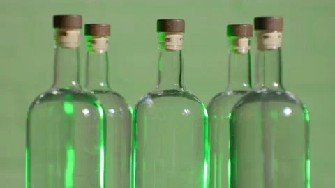 The bartender takes a bottle of alcohol from a table of several bottles of vodka Stock Footage 185187847