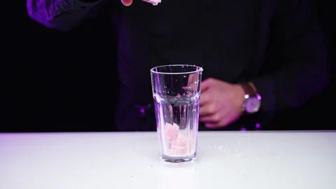 Bartender throws ice into glass, spills the cubes past the dishes on the table Video stock 168965706