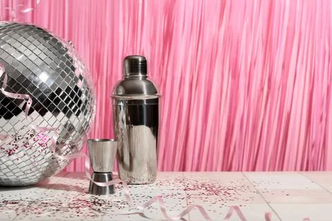 Bartender tools and disco ball on white tile table near pink wall Stock Photos
