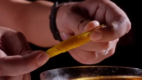 Bartender Twisting Citrus Peel Above Cocktail in Moody Bar Lighting Stock Footage 337862508