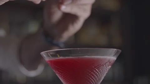 A bartender twists an orange peel and puts it in a red cocktail Stock Footage 135452219