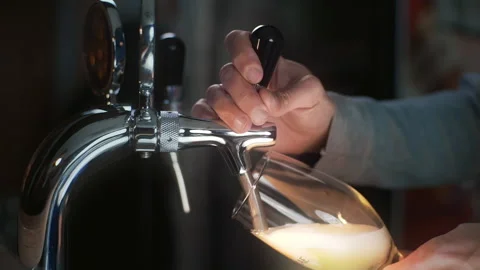 Bartender uses beer tap and pours draft beer to the glass in slowmotion Video stock 143590119