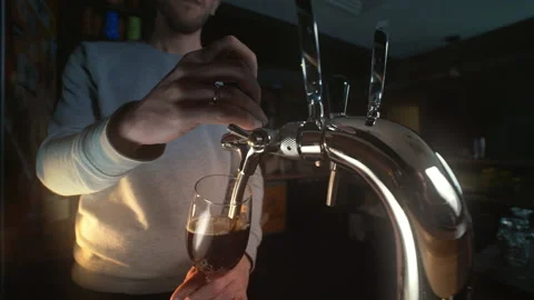 Bartender uses beer tap and pours draft beer to the glass in slowmotion Stock Footage 143590208