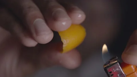 A bartender uses the juice of an orange to ignite the flame of a lighter Stock Footage 135452229