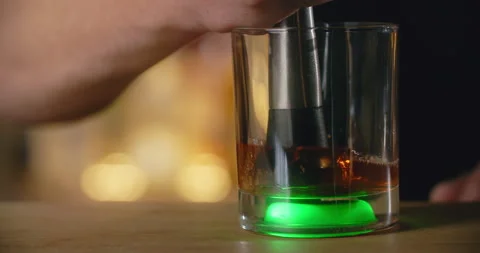 Bartender uses mudler for crushing the lump shugar in the cocktail glass on the Stock Footage 156256986