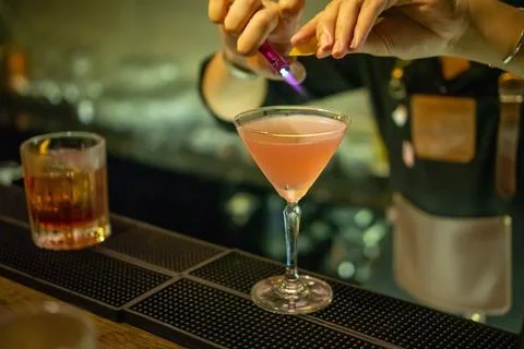 Bartender using a Storm Lighter to burn Lemon Drops to prepare a Cocktail i.. Stock Photos