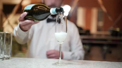 A bartender in a white shirt with one hand holds a bottle of sparkling wine and Stock Footage 201877008