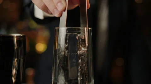 Bartender who puts a piece of ice in a glass before pouring a cocktail Stock Footage 219112992