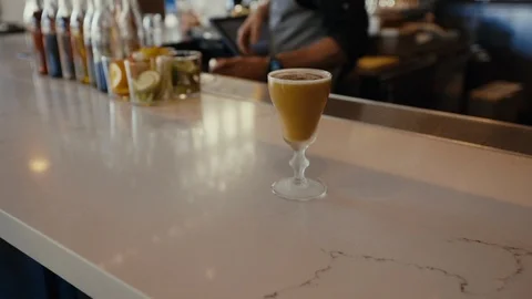 Bartender working behind bar with finished cocktail on bartop Stockbeeldmateriaal 99599309