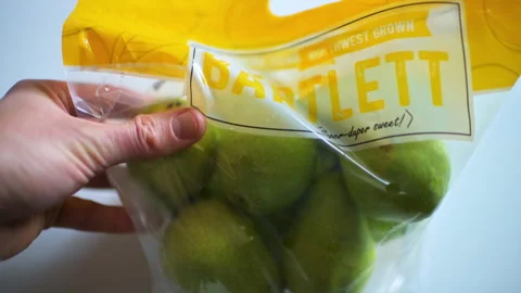 Bartlett pear, pears fruit in plastic bag macro closeup hand holding package Vidéo 330144273