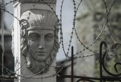 A bas-relief of a sad-looking human face surrounded by barbed wire. Stock Photos